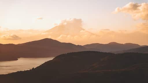 View of the majestic Mount Fuji rising through the clouds, a serene lake reflecting the soft golden light of dusk, Mt. Taikan Observation Deck, Yugawara, Kanagawa, Japan.