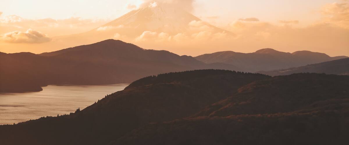 A mountain range with a prominent peak, a valley, and a body of water.