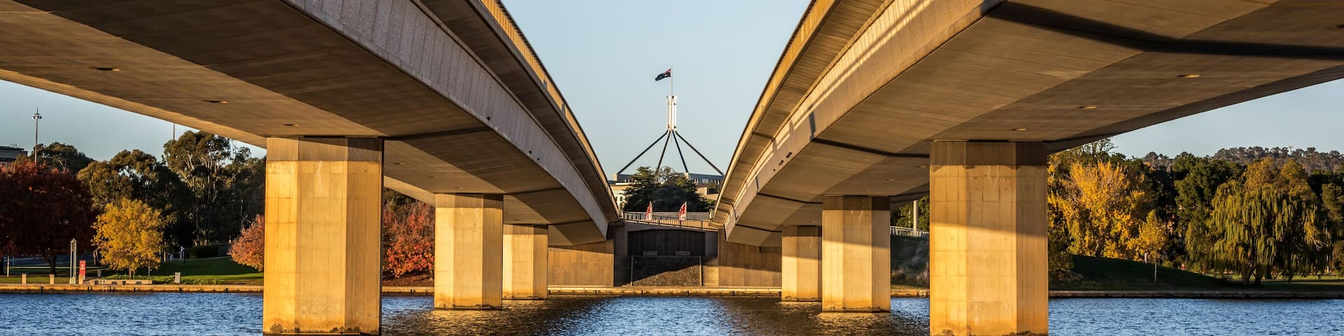 The Commonwealth Bridge is soaked in warm sunlight at sunrise.