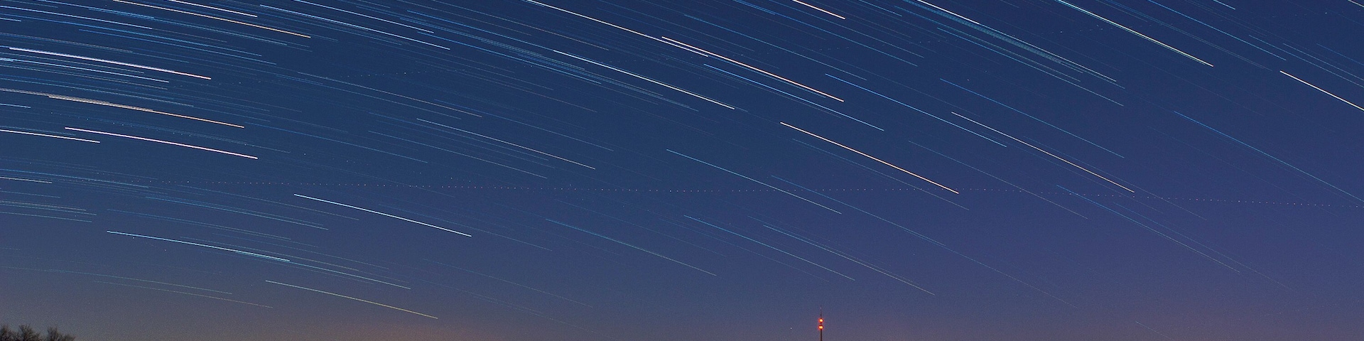Eine Fotomontage aus 60 Aufnahmen à 29 Sekunden des Schafbergs und Löbauer Fernsehturms unter Sternenhimmel und bei aufgehendem Vollmond. Die zwei hellen Linien im Vordergrund zeigen die Bundesstraße B6 sowie die Bahnverbindung Löbau-Görlitz.