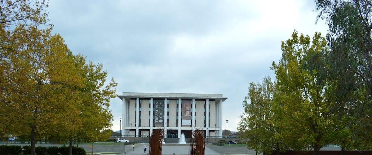 A building with a modern design, surrounded by a landscaped area with trees and shrubs.