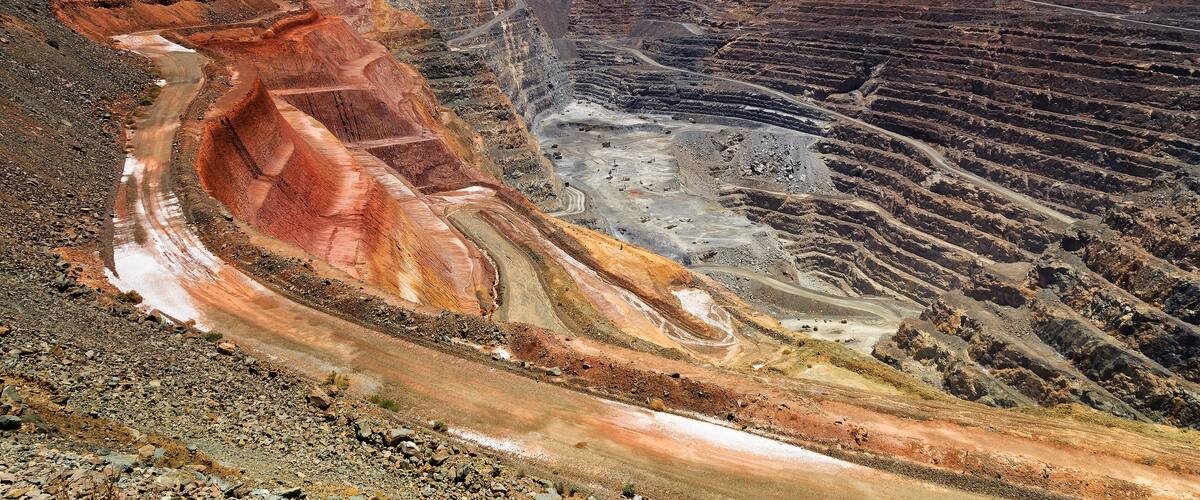 Una gran mina a cielo abierto con áreas de excavación escalonadas y un camino sinuoso.