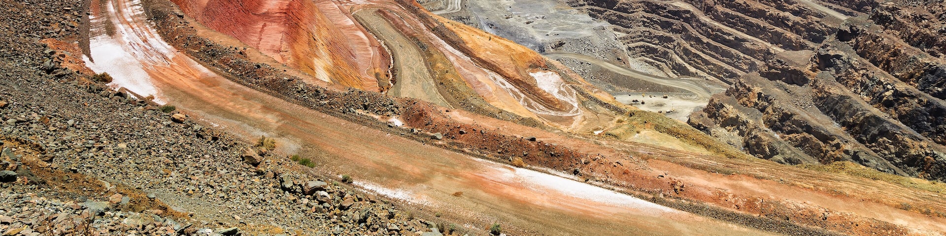 A large open-pit mine with terraced excavation areas and a winding road.