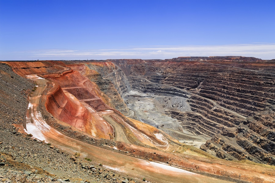 A large open-pit mine with terraced excavation areas and a winding road.