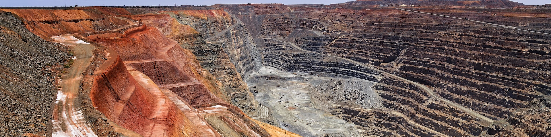 A large open-pit mine with terraced excavation areas and a winding road.