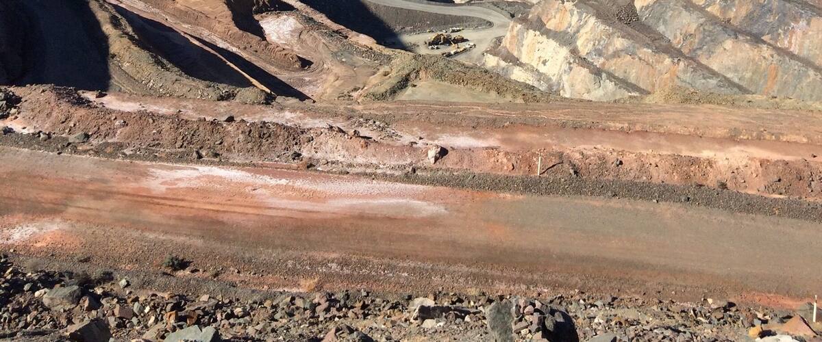 A vast open-pit mine with layered earth and a clear blue sky.