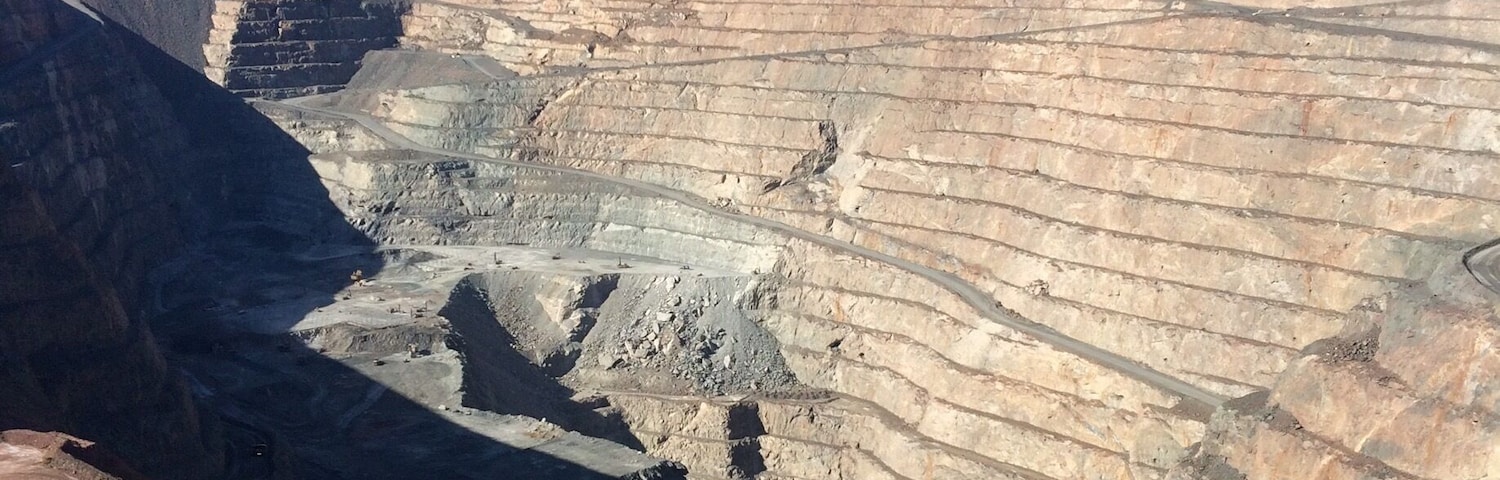 A vast open-pit mine with layered earth and a clear blue sky.