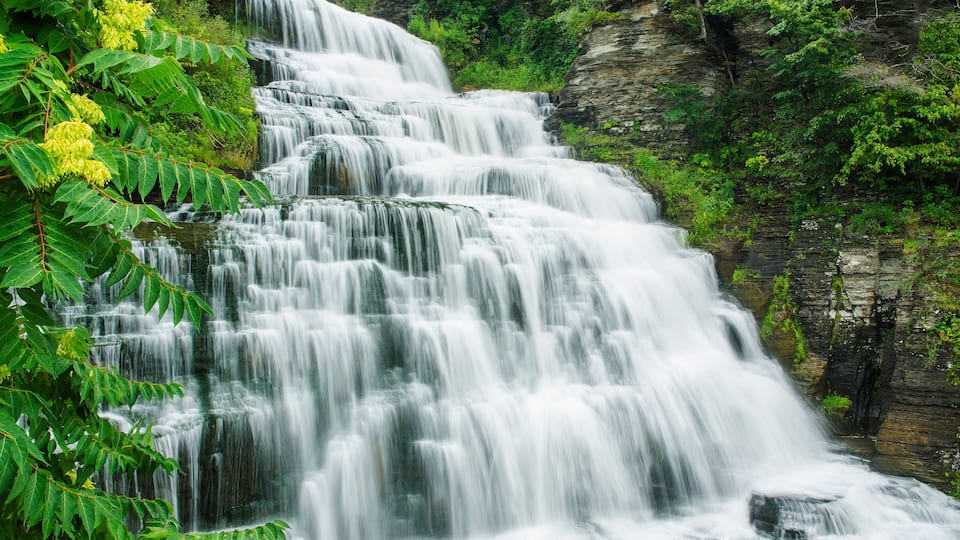 A multi-tiered waterfall surrounded by lush greenery.