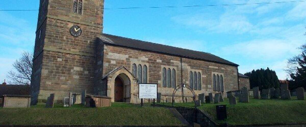 A church with a clock tower and a sign indicating directions to nearby towns.