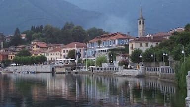 A lakeside town with a prominent church tower, buildings along the shore, and mountains in the background.