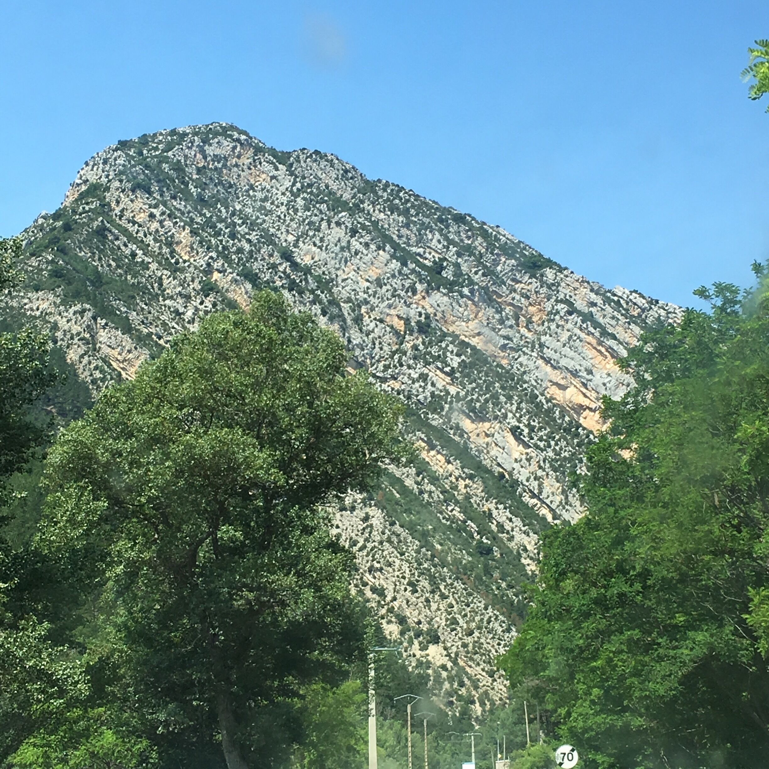 A mountain with rocky terrain and dense green foliage in the foreground.