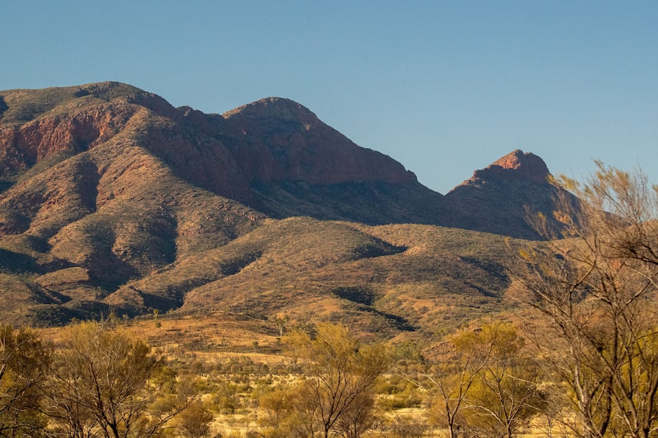 A mountainous landscape with sparse vegetation and clear skies.