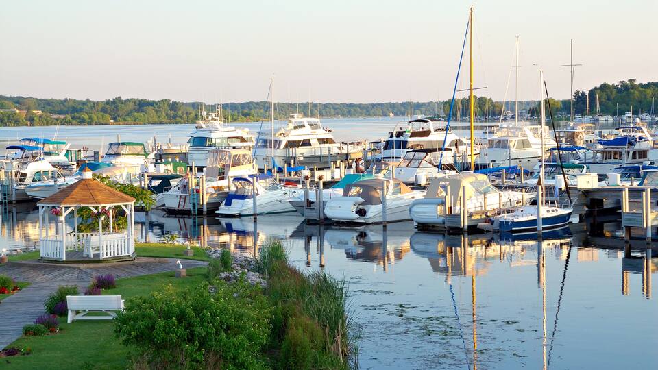 A marina with various boats docked, a gazebo, and a wooden walkway.