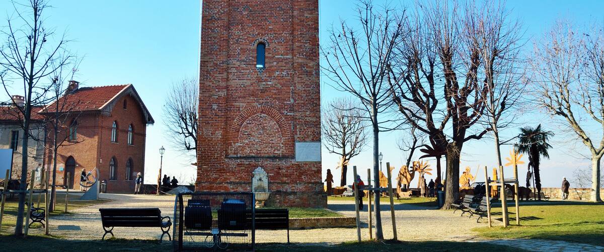 A brick tower, a park with benches, and leafless trees.
