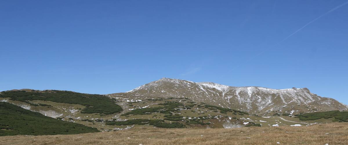 Eine Bergkette mit grüner Vegetation und Schneeflecken.