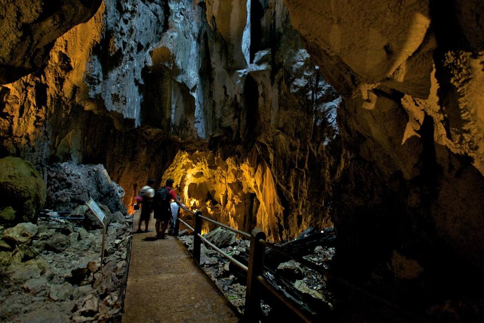 A cave with a wooden walkway and people exploring.