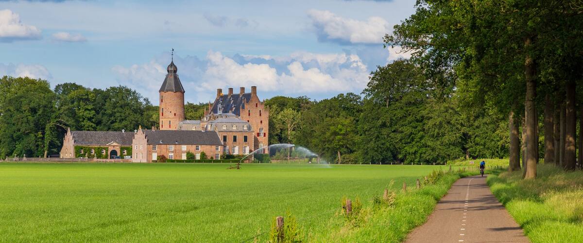 A historic castle with a tower, surrounded by a lush green field and a pathway.