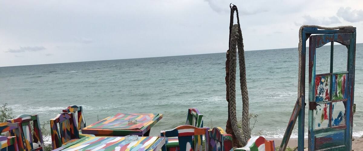 Colorful beach chairs and tables, a rope swing, and a weathered door with a mural.