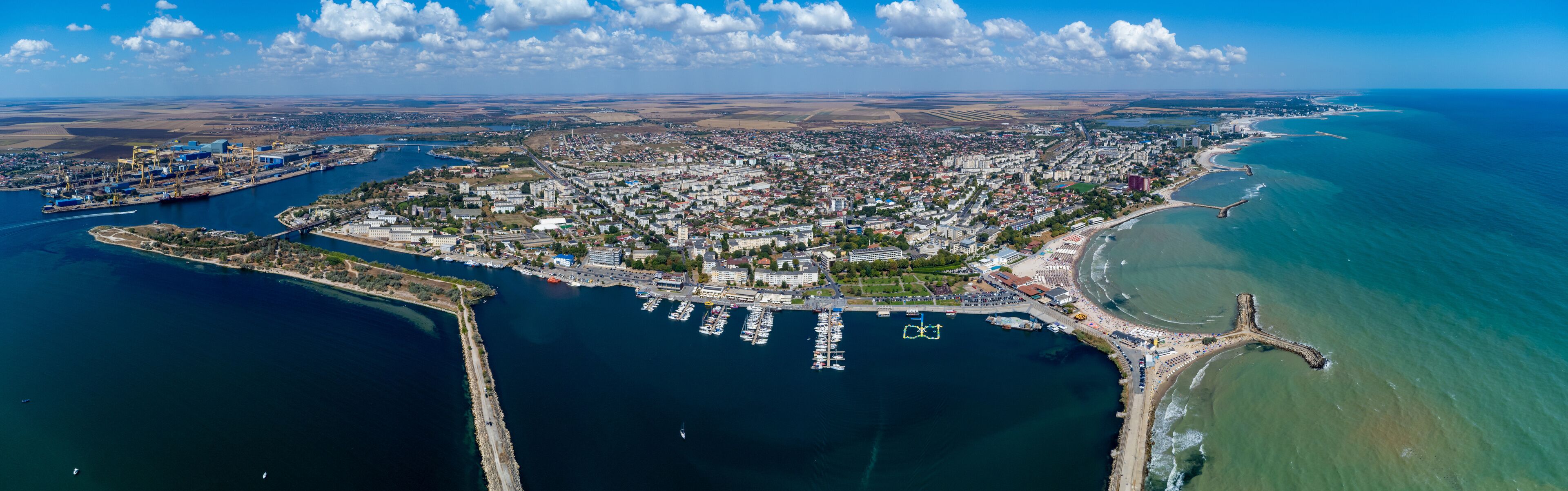 An aerial view of a coastal city with a harbor, a bridge, and a lighthouse.