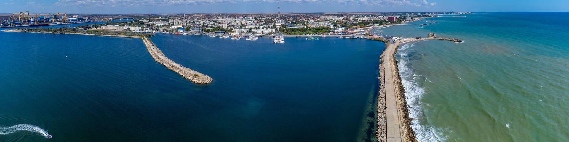 A coastal city with a marina, a breakwater, and industrial cranes.