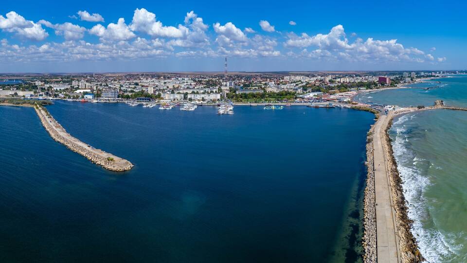 A coastal city with a marina, a breakwater, and industrial cranes.