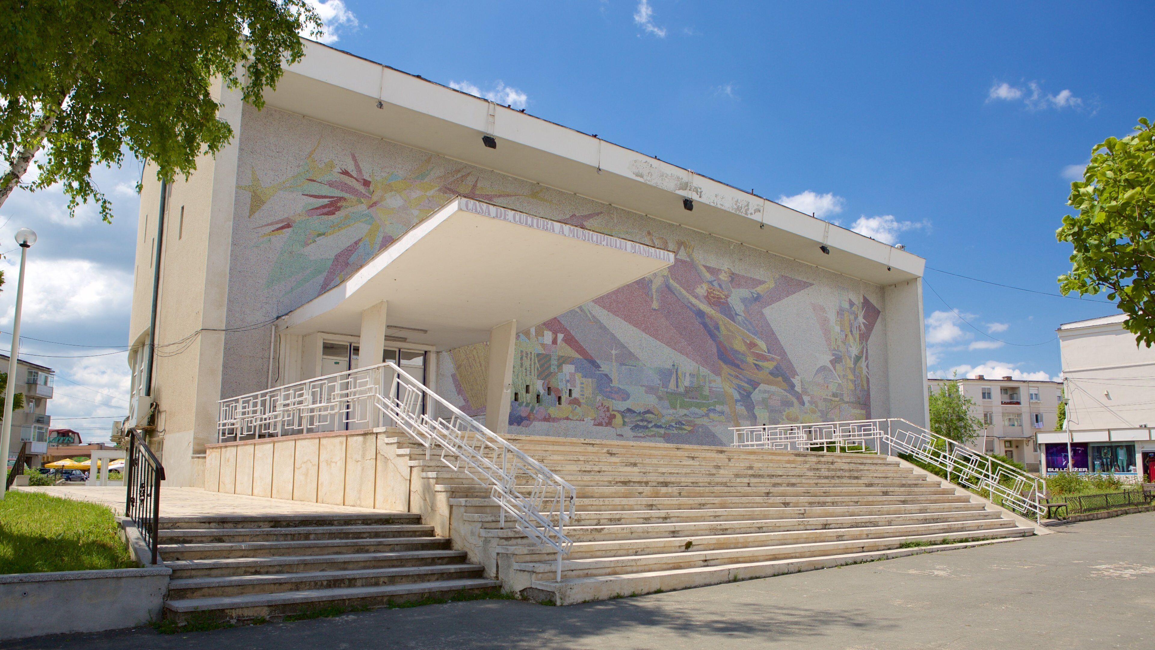 A building with a colorful mural and a staircase leading to the entrance.