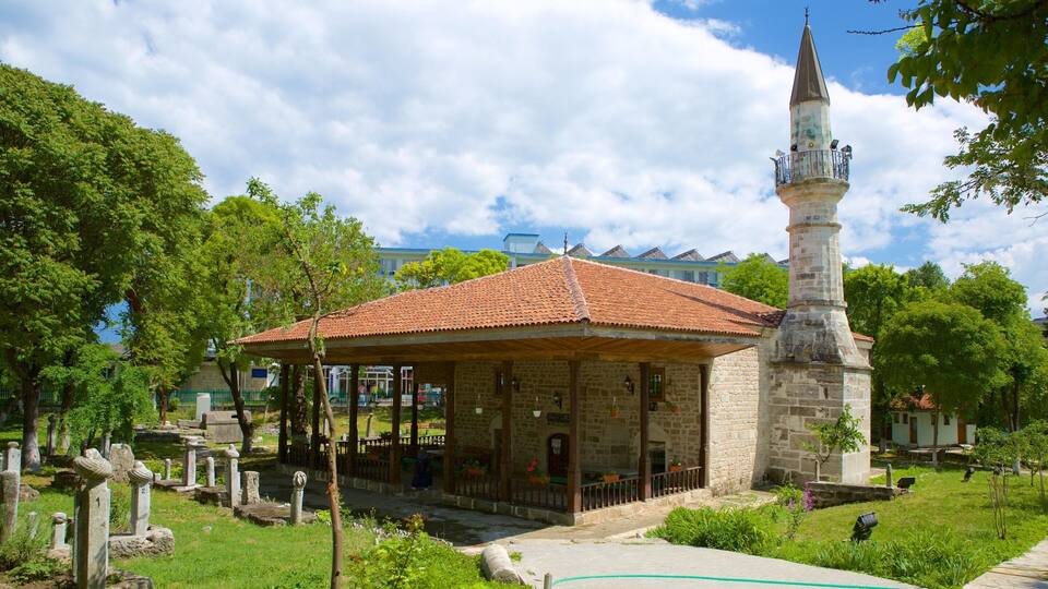 A stone building with a tiled roof and a tall tower with a pointed roof.
