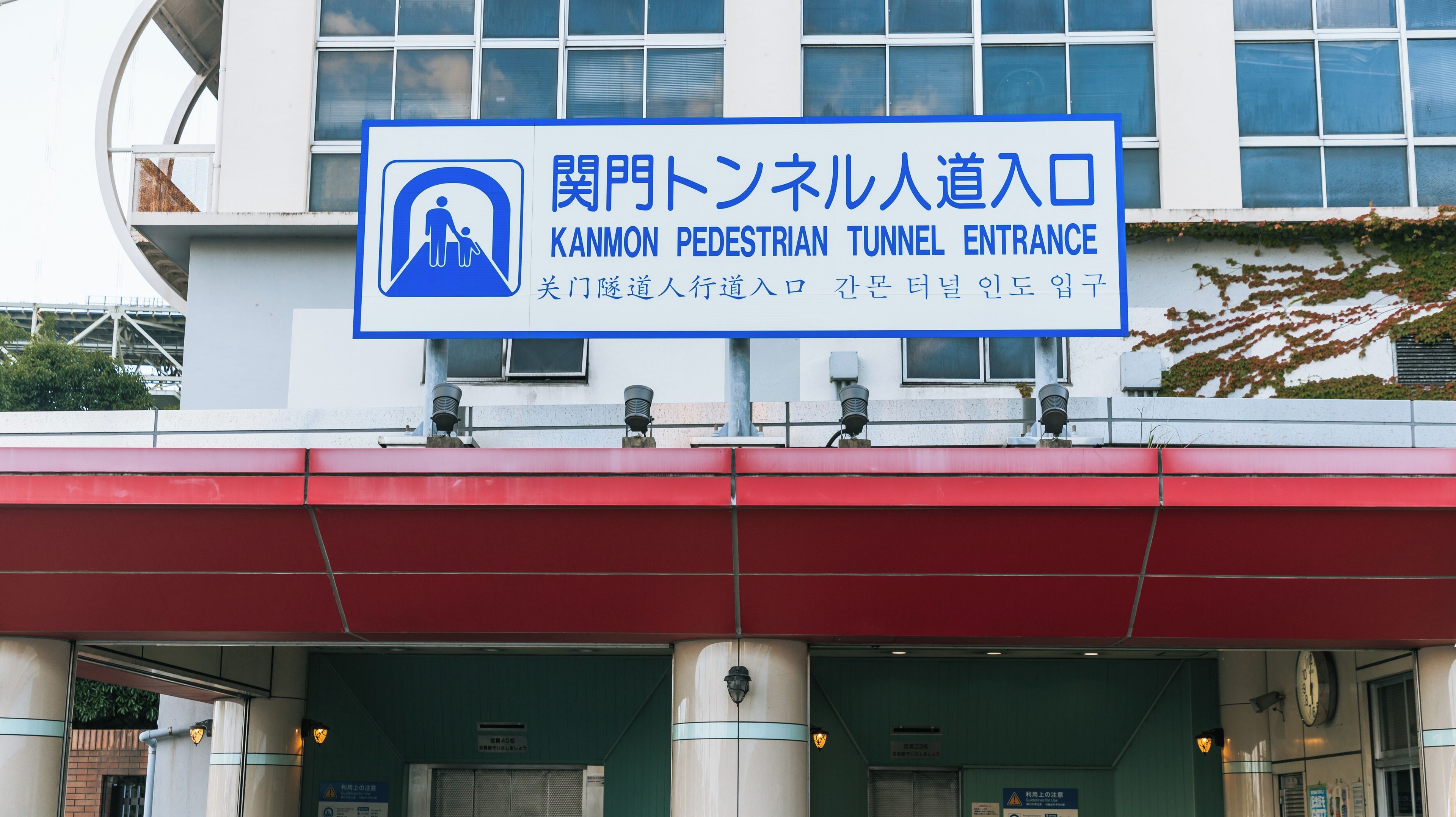 A pedestrian tunnel entrance sign with Japanese text and an icon of a person with a child.