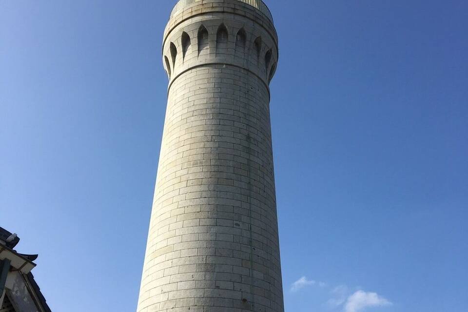 Uma torre alta e cilíndrica com cúpula, construída com tijolos claros, sob um céu azul límpido.