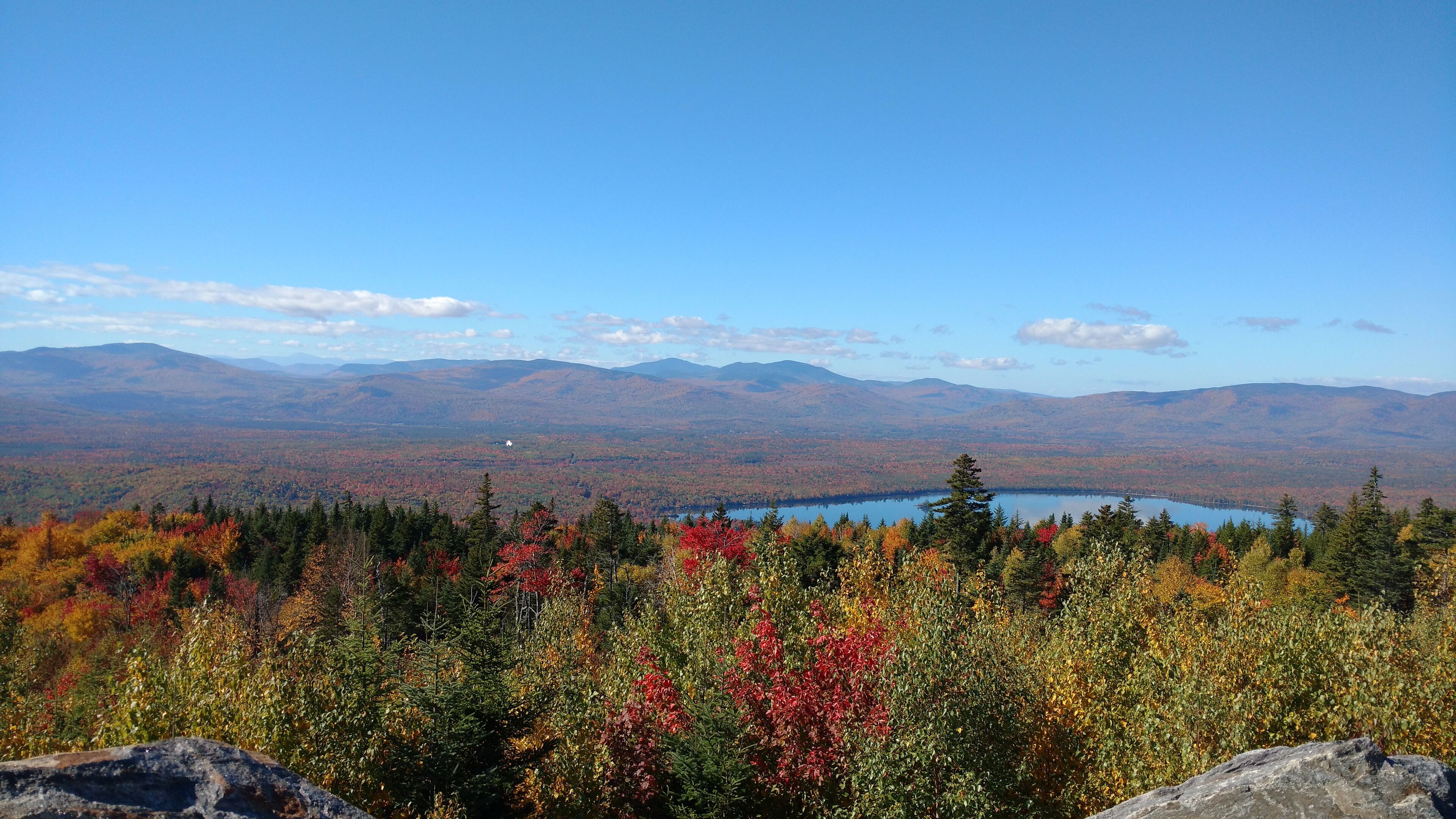 A mountainous landscape with autumn foliage and a lake.