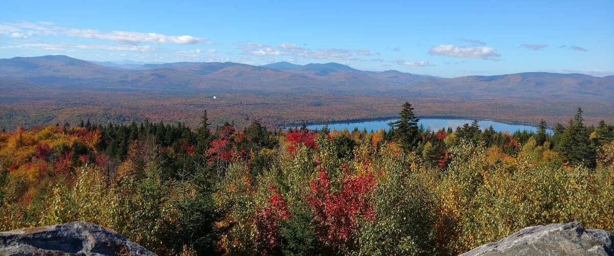 A mountainous landscape with autumn foliage and a lake.