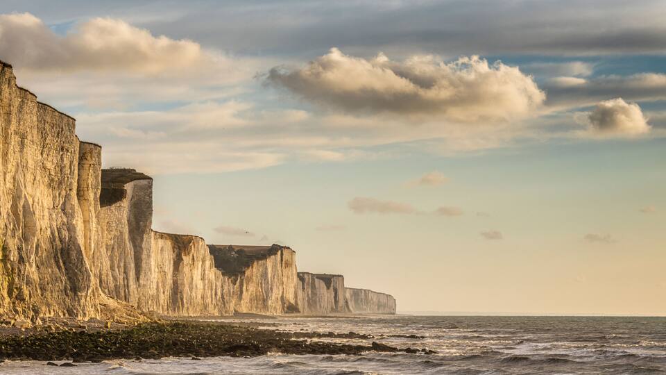 A coastal cliff formation with a rugged coastline and a clear sky.