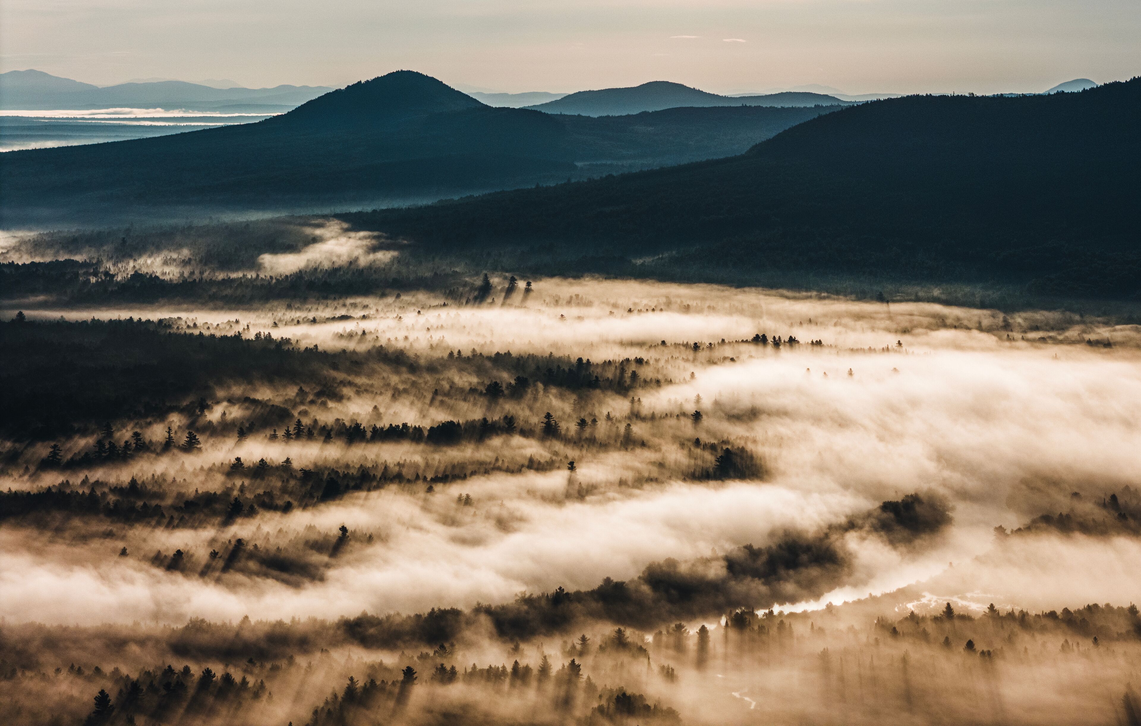 Morning mist settles over the Dead River with mountains.