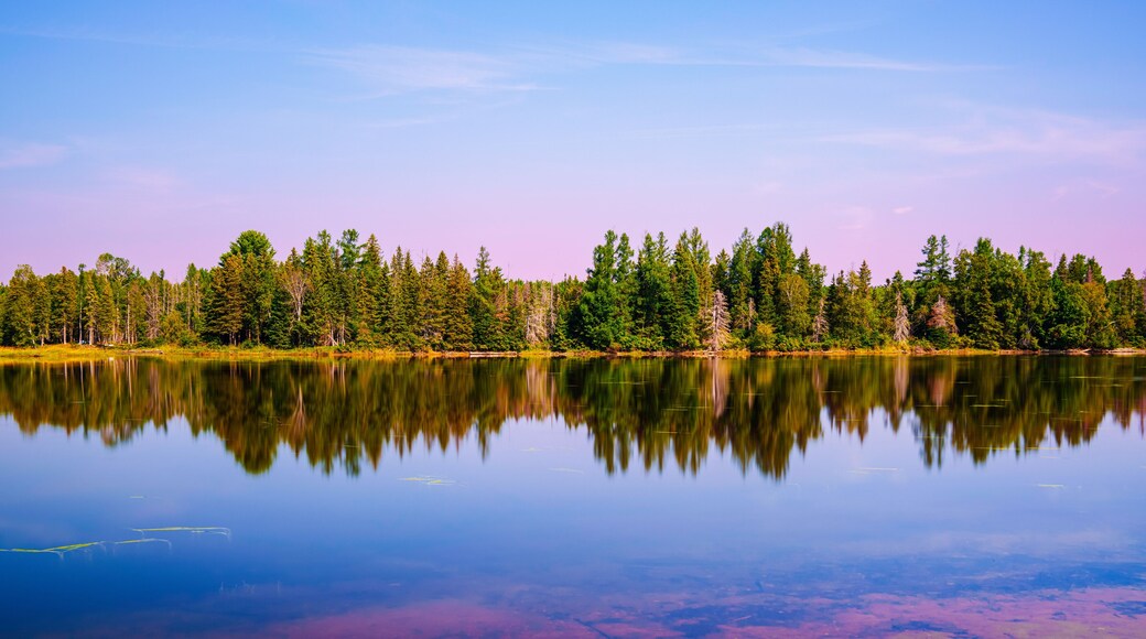 Early autumn sunrise landscape over Flagstaff Lake in Maine with water reflections of the pine forests, a quiet moment in the heart of New England.