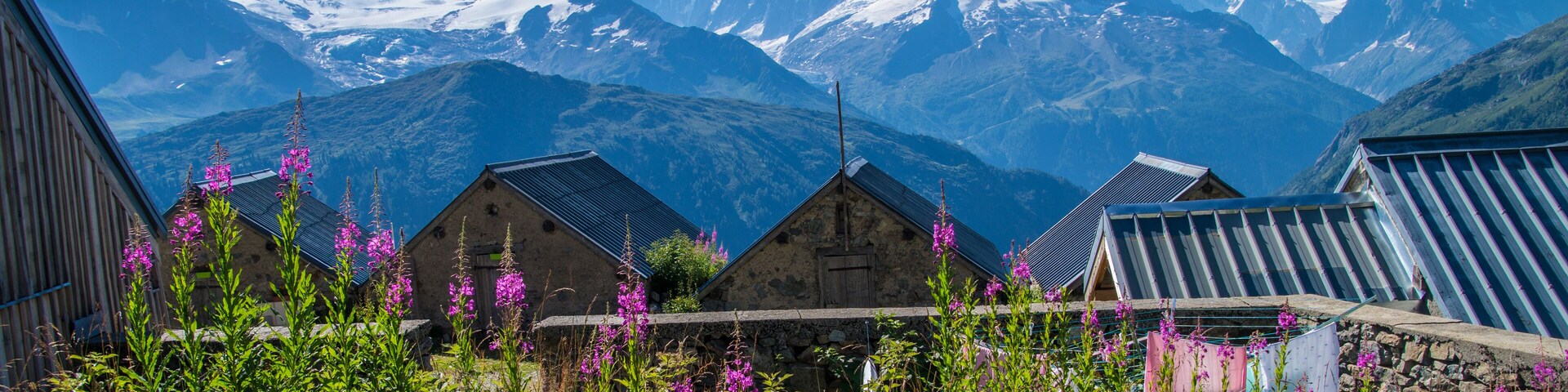 Un pueblo de montaña con casas de madera tradicionales y picos nevados al fondo.