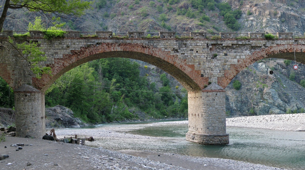 Un pont de pedra amb dues voltes sobre un riu, envoltat de terreny rocos i vegetació.