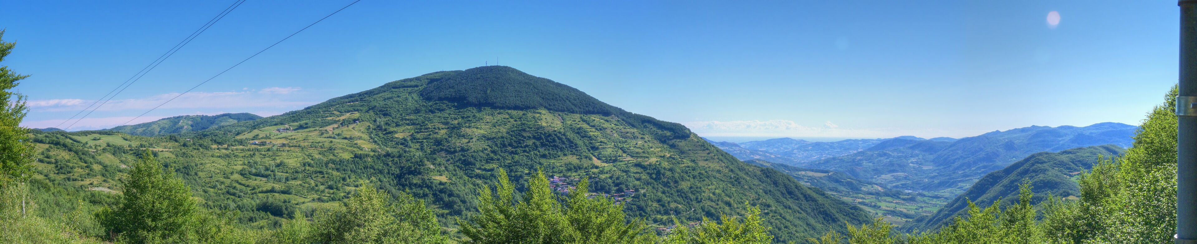 A mountain landscape with lush greenery and a clear blue sky.