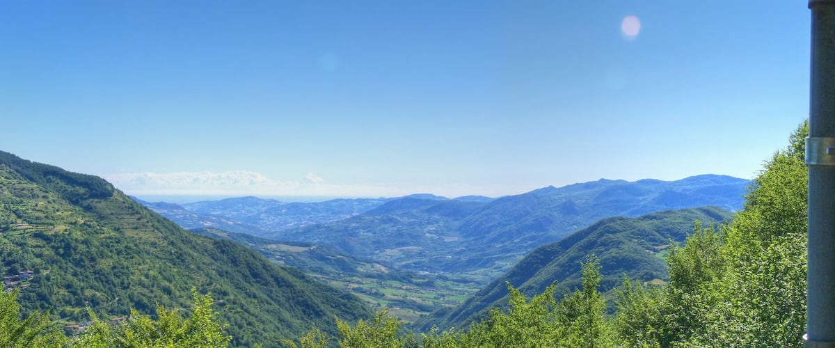 A mountain landscape with lush greenery and a clear blue sky.