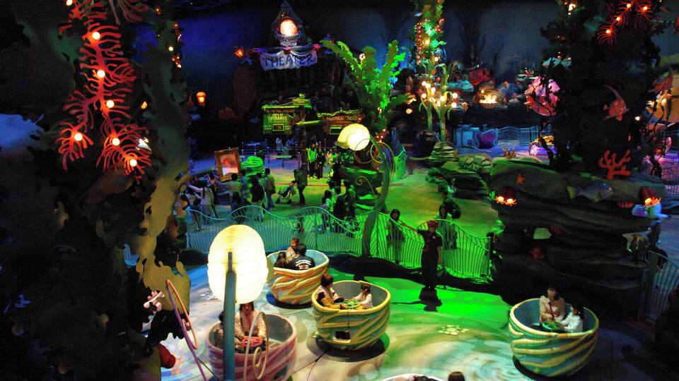 A themed indoor amusement park with a whimsical, fantasy setting, including a large tree, a castle, and various rides.