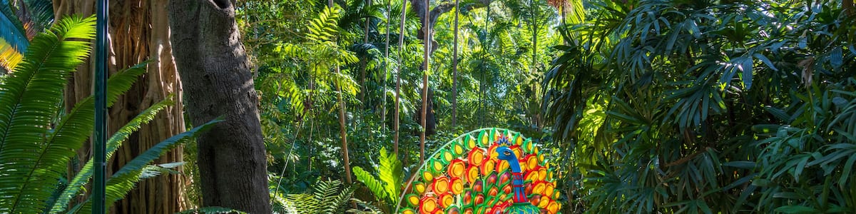 A pathway through a lush forest with a colorful mural on a stone archway.