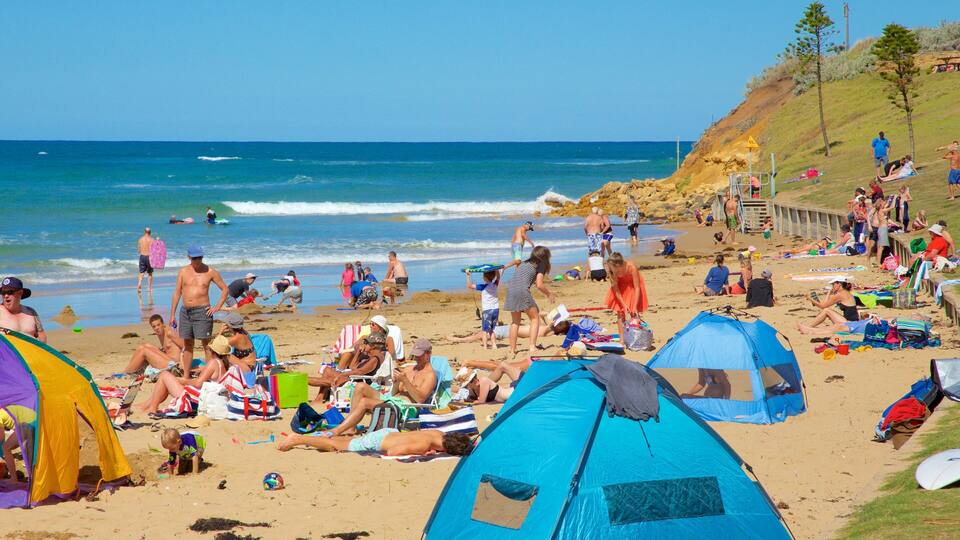 Ein voller Strand mit Personen, die sonnenbaden, spielenden Kindern und aufgebauten Zelten.