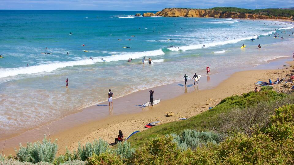 A beach with surfers, waves, and cliffs.