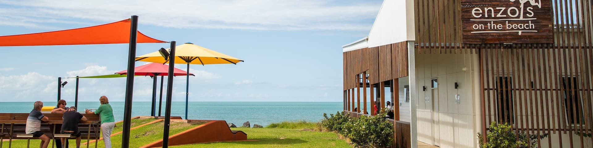 A beachside restaurant named 'enzols on the beach' with outdoor seating and colorful umbrellas.