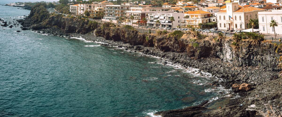 A coastal town with buildings along the rocky shoreline and a clear view of the ocean.