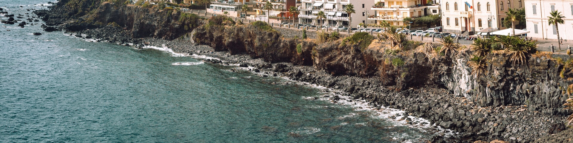 A coastal town with buildings along the rocky shoreline and a clear view of the ocean.