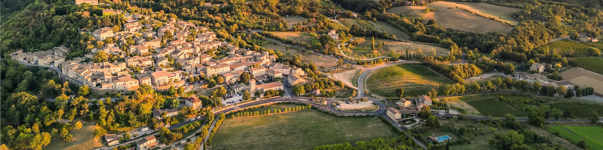 Panoramic drone view of one of the most beautiful French towns in southern France - Mirmande. Old historic town. Sunset over the surrounding mountains. Chimneys from the power plant in the distance