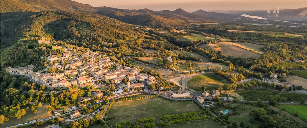 A mountainous landscape with a small town nestled in the valley, surrounded by fields and vineyards.