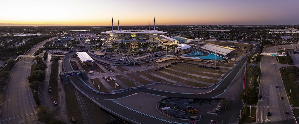 Miami Gardens, USA - 23 February 2026: Aerial view of Hard Rock Stadium and the vibrant Formula 1 Miami International Autodrome under a fading sunset sky.