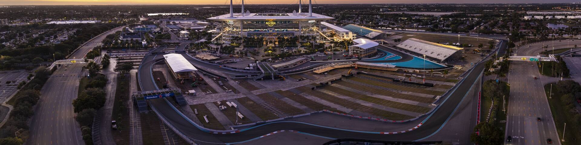 Miami Gardens, USA - 23 February 2026: Aerial view of Hard Rock Stadium and the vibrant Formula 1 Miami International Autodrome under a fading sunset sky.