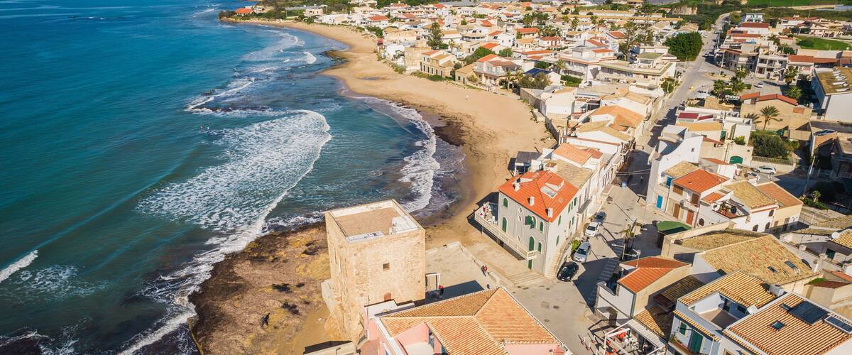 A coastal town with a beach, buildings, and the sea.